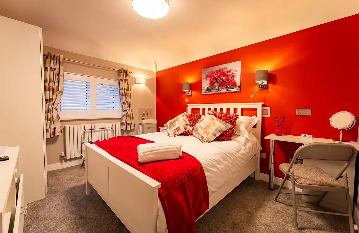 Room Three with bold red wall and queen-size bed